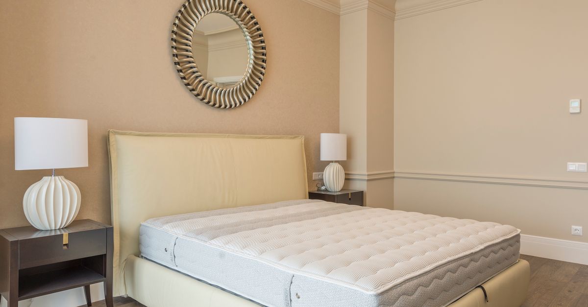 A neatly made bed in a calm, neutral bedroom