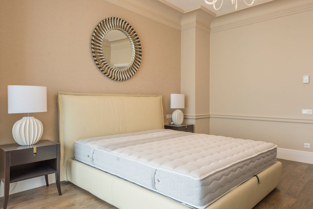A neatly made bed in a calm, neutral bedroom